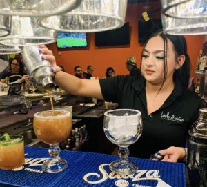 A woman bartender pours a spicy margarita.