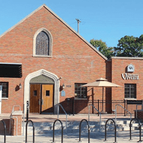 A table and umbrella set up in front of a brewery that looks like a chapel.