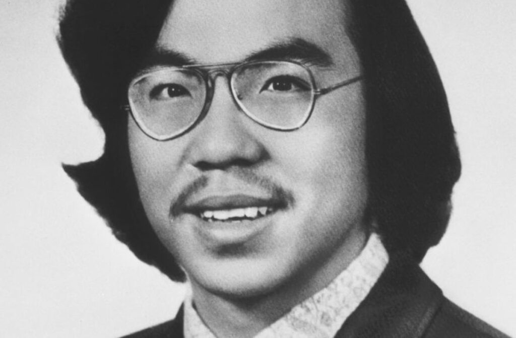 Vincent Chin smiling for a photo, wearing glasses and a suit.