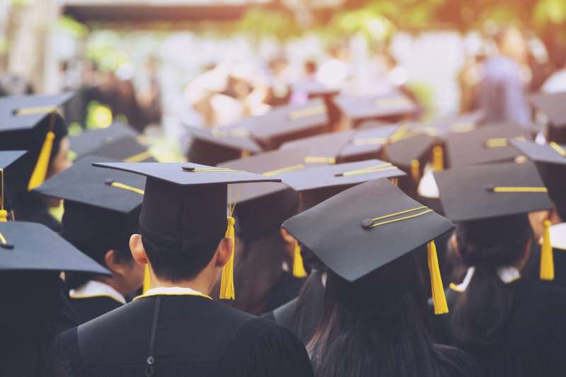 Students at high school graduation. Wearing cap and gown. Celebrating educational achievement