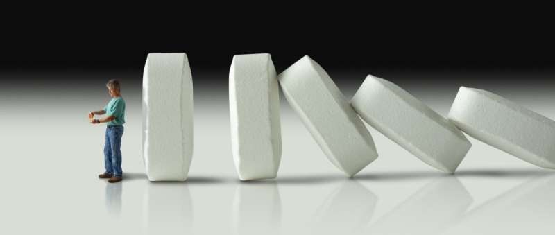 Impending doom and demise of man with pharmaceutical opioid pain medication addiction represented by huge row of pills crashing over like dominoes to eventually crush the man.