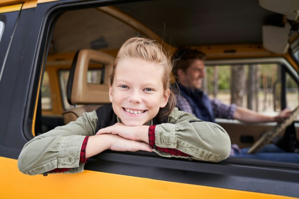 Young girl smiling in a car traveling on Thanksgiving.