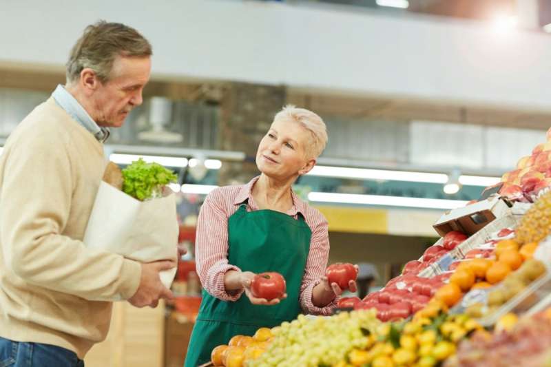 Man and woman in grocery store looking at fruit.