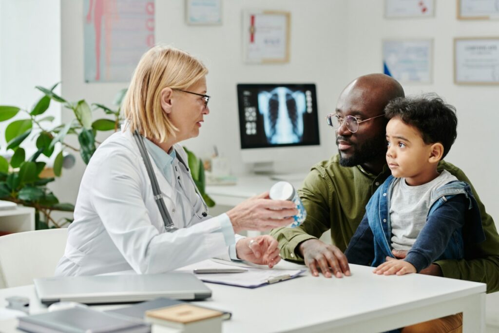 a doctor speaks to a man and his son in an office