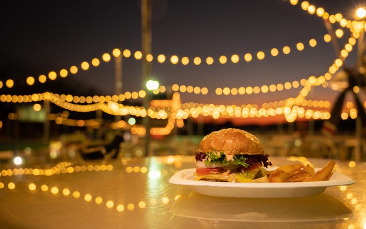 A burger served on table against light bokeh in night party.