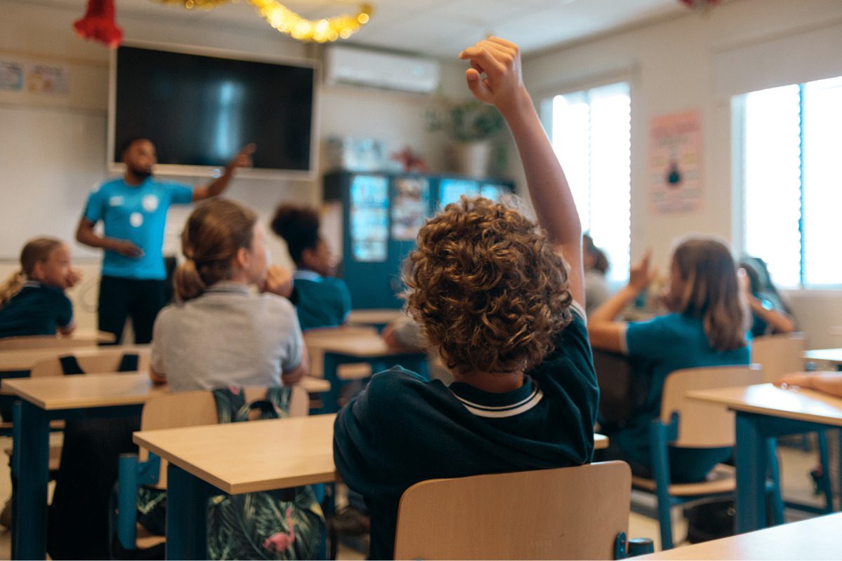 Students in a classroom, boy raising hand
