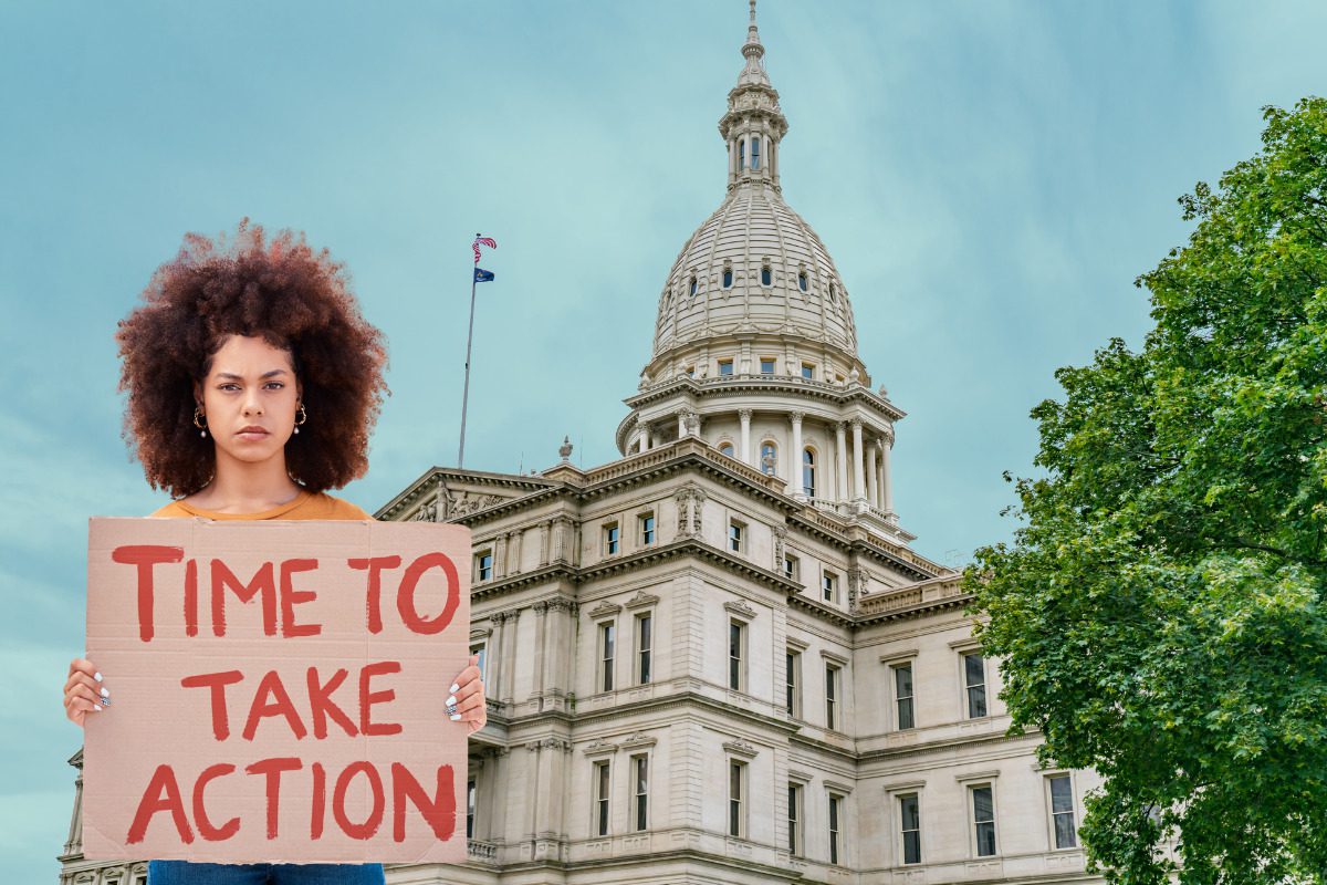 Woman with protest sign reading "time to take action" Michigan State Capitol Building edited in background
