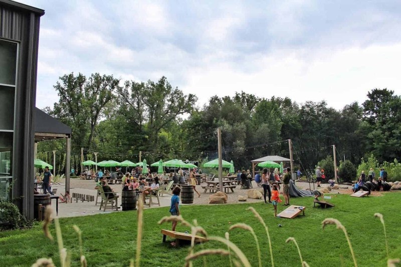 Kids playing yard games alongside a patio with picnic tables and fire pits at Third Nature Brewing, one of Michigan's breweries