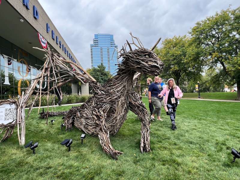 A woman looks over a dragon made out of driftwood.